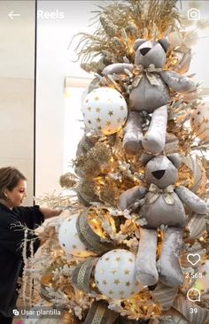 a woman decorating a christmas tree with gold and silver decorations on it's sides