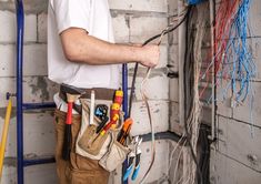 a man is working on electrical wiring in his home or office, with tools and wires attached to the wall