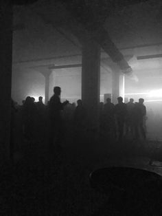 black and white photograph of people standing in a dark room with light coming through the window