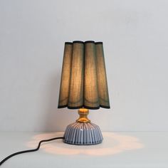 a lamp that is sitting on top of a white table with a black cord attached to it