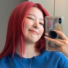 a woman with red hair taking a selfie in front of a mirror while wearing a blue shirt