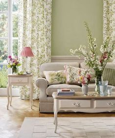 a living room filled with furniture and flowers in vases on top of a table