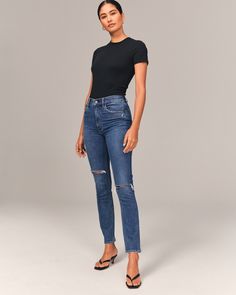 Our high rise skinny jean with figure-defining style and built-in stretch for superior comfort. With a form-fitting silhouette from top to bottom, this style is cropped to show a little ankle-and your favorite shoes. Featuring a medium wash, trendy knee slash details and distressed hem. Shirt Tucked In, Jeans Mid Rise, Women's Bottoms, Abercrombie And Fitch Jeans, How To Stretch Boots, High Waisted Jeans, Edgy Look, Mid Rise Jeans, High Rise Jeans