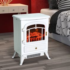 a small white stove in a bedroom next to a night stand with a red light on it