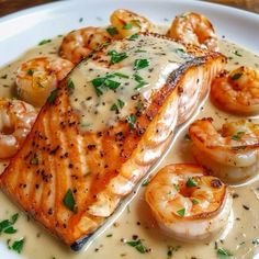 grilled salmon with shrimp and scallops served on a white sauce covered plate