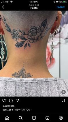 the back of a woman's neck is shown with tattoos and piercings on it