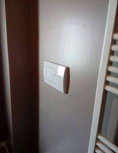 an electrical outlet on the wall next to a radiator and towel rack in a bathroom