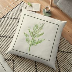 a green plant is sitting on the floor next to a book and coffee mugs