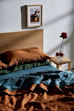 a bed with brown sheets and two vases on the end table next to it