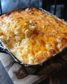 a casserole dish with macaroni and cheese in it on a wooden cutting board