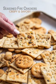 someone is picking up some crackers from a baking pan with the words seasoned fire crackers crispy and savory