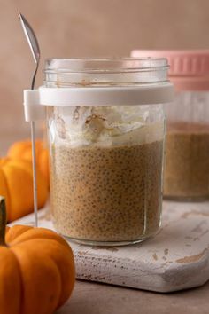 a jar filled with food sitting on top of a table next to two pumpkins