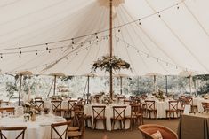 the inside of a large tent with tables and chairs set up for an outdoor wedding