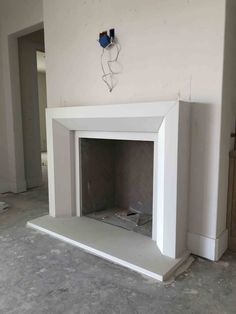 a white fireplace in the middle of a room with no one around it on the floor