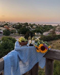 a table topped with fruit and vegetables on top of a wooden fence next to the ocean