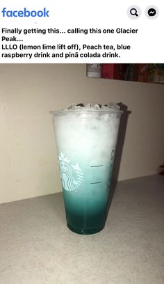 a starbucks cup with blue and green liquid on the bottom, sitting on a counter