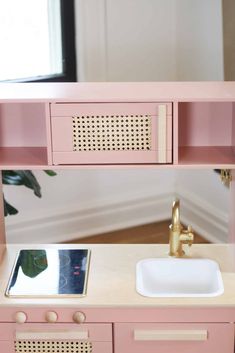 a pink and gold bathroom vanity with mirror, sink and faucet in it