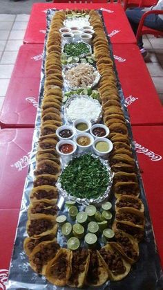 a long table topped with lots of food on top of a red tablecloth covered floor