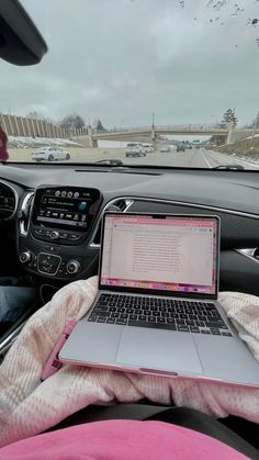 a laptop computer sitting on top of a pink blanket in the back seat of a car