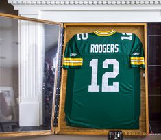 a green and yellow football jersey in a wooden case with the number 12 on it