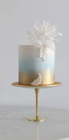 a white and blue cake sitting on top of a gold plated serving platter