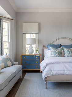 a white bed sitting next to a blue dresser in a bedroom