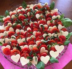 a platter filled with lots of tomatoes and hearts on top of pink napkins