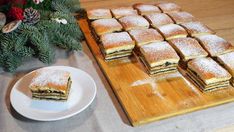 a wooden cutting board topped with lots of desserts next to a plate of food