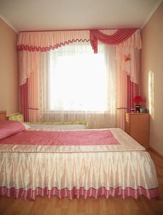 a pink and white bed in a bedroom next to a window with curtains on the windowsill