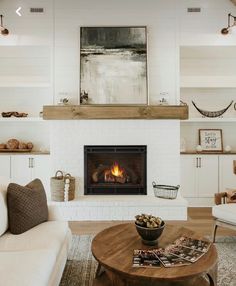 a living room with white furniture and a fire place in the middle of the room