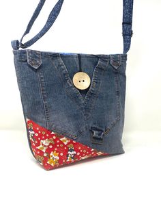 a denim purse with a button on the front pocket and floral fabric lining, hanging from a white background