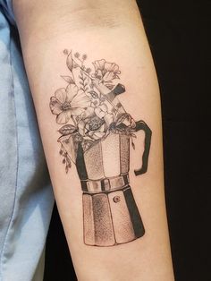 a tattoo on the arm of a person holding a coffee pot with flowers in it