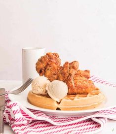 chicken and waffles on top of a white plate next to a cup of ice cream