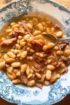 a bowl filled with beans and ham on top of a wooden table