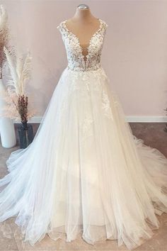 a white wedding dress on display in front of a pink wall and vase with flowers