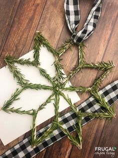 a piece of paper with some green leaves on it next to a black and white checkered ribbon