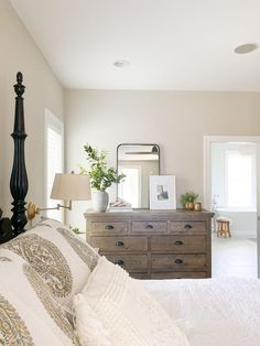 a bedroom with a bed, dresser and mirror on the wall in front of it