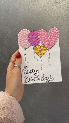 someone holding up a birthday card with balloons