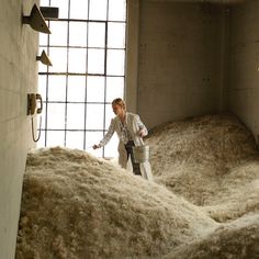 a woman standing next to a pile of hay in a room with bars on the wall