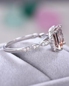 an engagement ring with a pink morganite surrounded by white diamonds on a velvet cushion