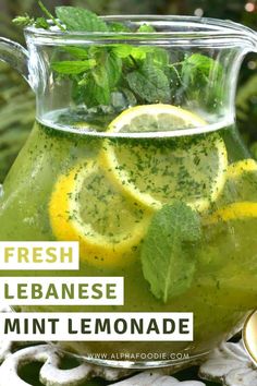 a pitcher filled with lemonade and mint garnish on top of a table