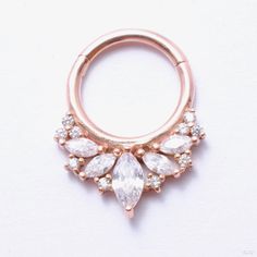 Like an ornate crown for your piercing, this solid gold hinged ring is a burst of sparkling gemstones. Marquise-cut stones of varying sizes are clustered together in a unique arrangement and accented by ten 1mm matching stones, all prong-set to allow for maximum brilliance. Elegant Cubic Zirconia Septum Ring With Diamond Accents, Elegant Cubic Zirconia Septum Ring With Prong Setting, Elegant Septum Ring With Prong Setting In Cubic Zirconia, Gold Cluster Jewelry With Sparkling Stones, Elegant Diamond Septum Ring With Accents, Elegant Wedding Septum Ring, Cubic Zirconia Cluster Jewelry With Sparkling Stones, Elegant Wedding Septum Ring With Prong Setting, Elegant Hoop Septum Ring With Prong Setting