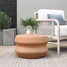 an outdoor living area with a chair, table and potted plant on the floor