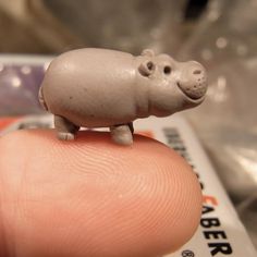 a tiny toy hippo sitting on top of a finger