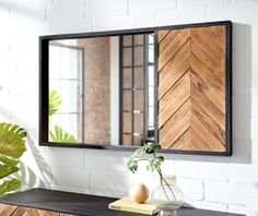 a mirror on the wall above a dresser with a potted plant in front of it