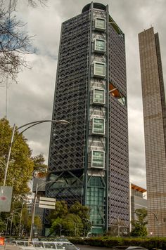 the tall building has many windows on it's sides and is surrounded by other buildings