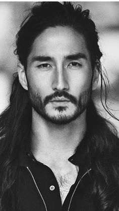 a black and white photo of a man with long hair