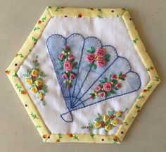 a close up of a piece of cloth with flowers and an embroidered fan on it