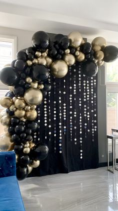 black and gold balloons are hanging on the wall