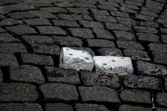 two white dices laying on top of a cobblestone road